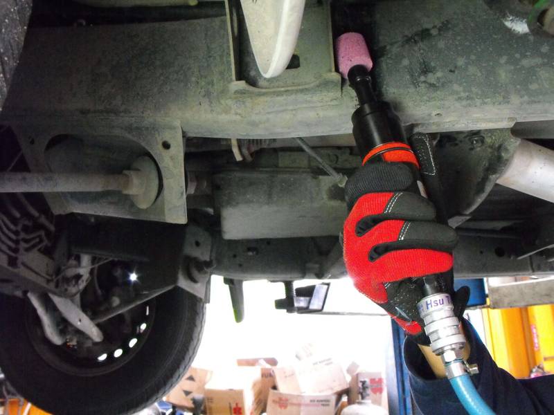 a man working on a vehicle under a vehicle