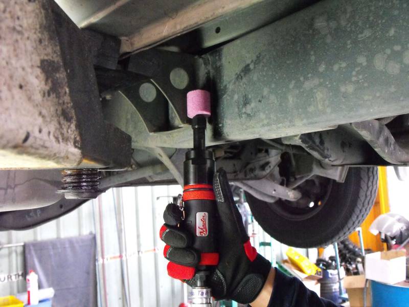 a man holding a wrench under a vehicle