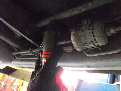 a close up of a person holding a wrench under a vehicle