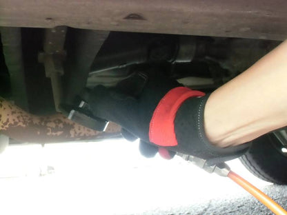 a person in black gloves working on a vehicle