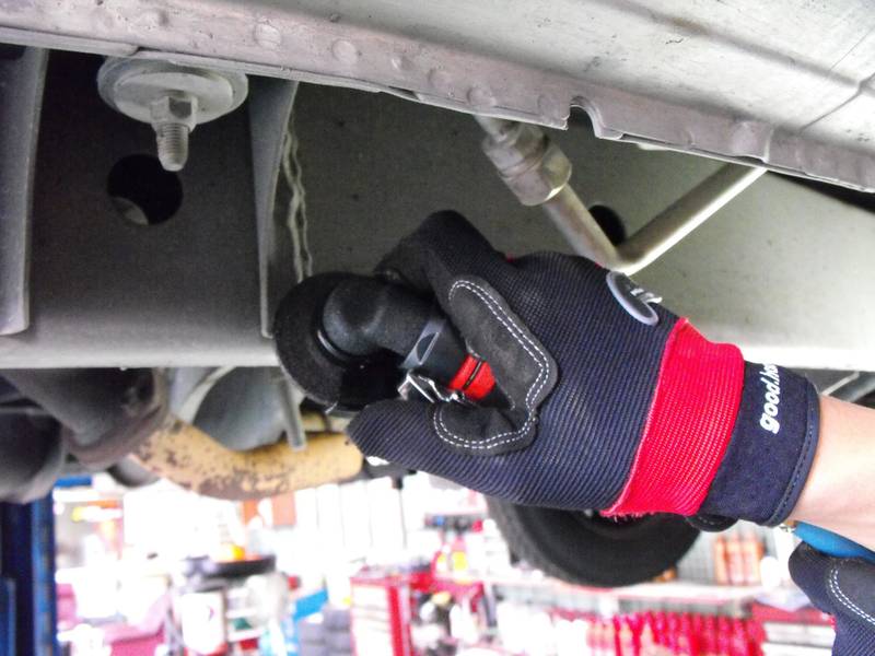 a mechanic working on the underside of a vehicle